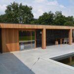 Modern houten bijgebouw aan zwembad en met sauna