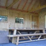 Landelijke buitenkeuken met lange houten tafel