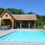 Houten poolhouse met rieten dak en terrasoverkapping