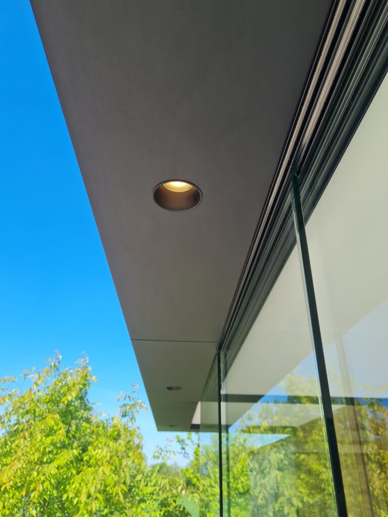 Detailaanzicht van de oversteek met spotjes bij een modern bijgebouw.