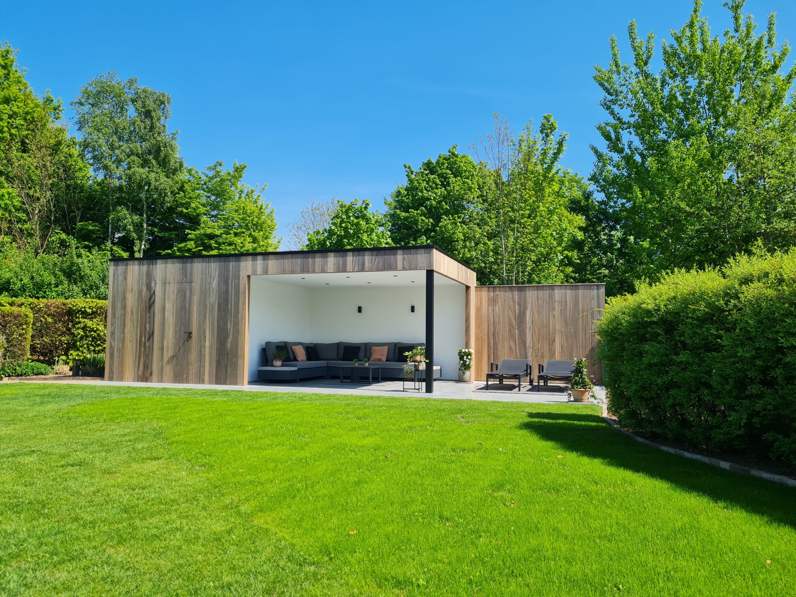 Moderne houten tuinberging met terrasoverkapping.