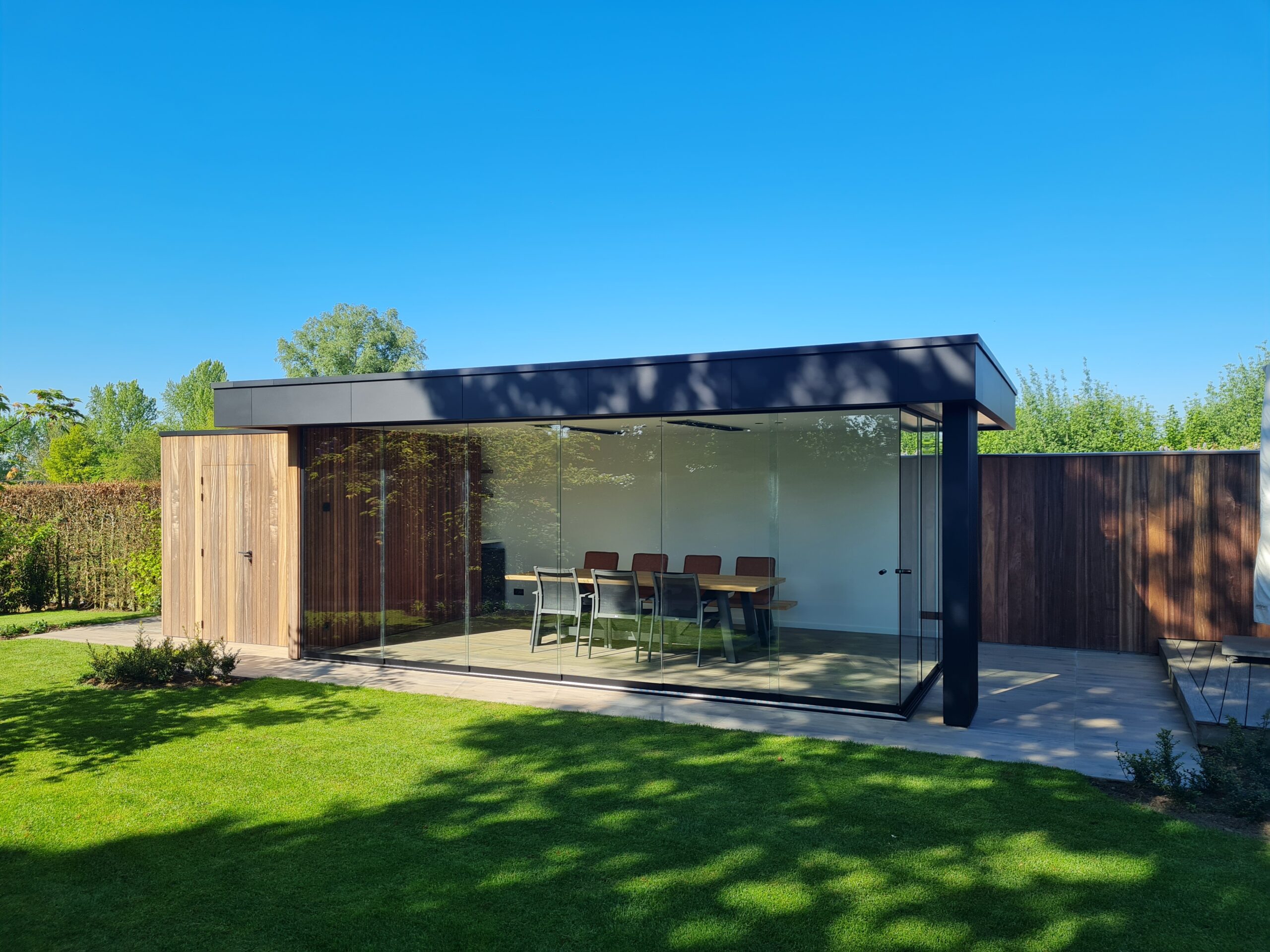 Modern bijgebouw met glazen schuifwand en tuinberging.