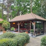 Eikenhouten terrasoverkapping en pannen dak. 1 gevel gesloten met glas.